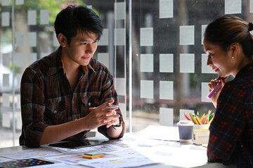 The Asian business partner discussing about a new project's idea with his partner in the modern...