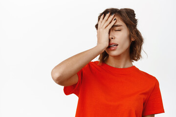 Facepalm girl. Disappointed young woman looking tired, slap face with hand, standing distressed and upset, white studio background