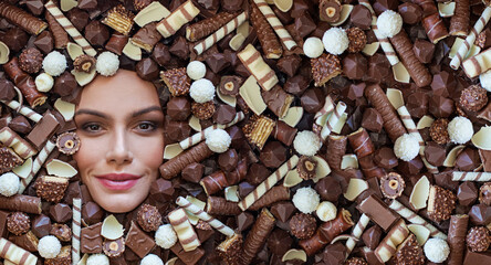Woman lying on brown chocolate and candies background. Creative chocolate and sweet concept