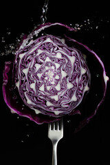 Red cabbage on a fork with water pouring, splashed with water drops on a black background