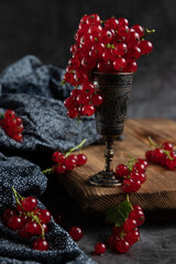 Red current in an iron glass, standing on a wooden table, branches of fresh berries, rustic style