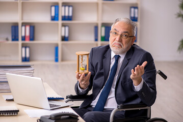 Old male employee in wheel-chair in time management concept