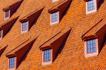 Many small windows on a red roof covered with tiles in the old town of Gdansk