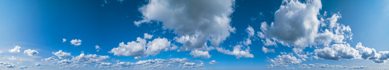 Blue sky with clouds in sunshine (wide natural cloudscape background panorama)