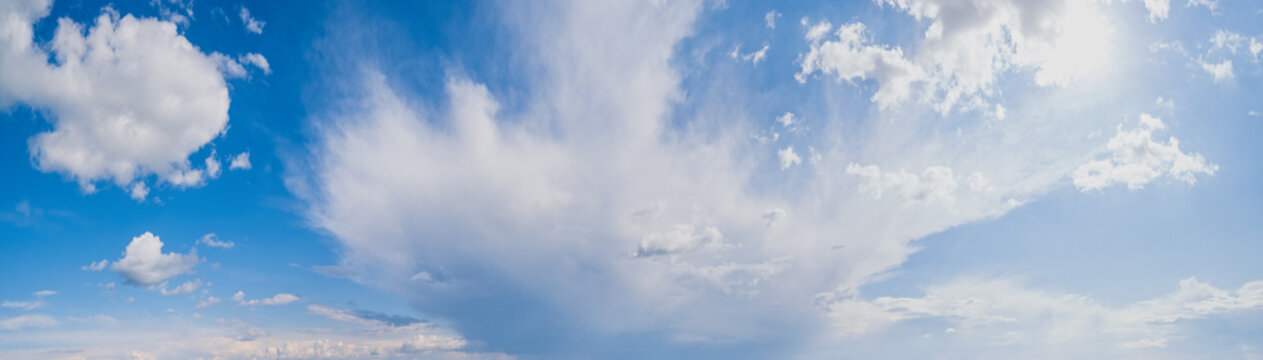 White cumulus clouds abd sunshine in blue sky panoramic high resolution background