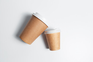 Close-up top view of two paper cups for coffee takeaway on white background.