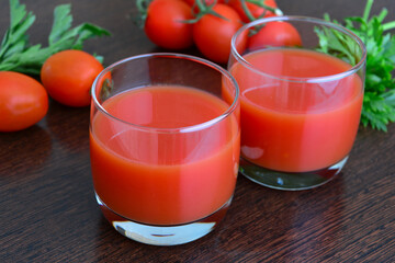 fresh tomato juice in drinking glasses on wooden background, close-up