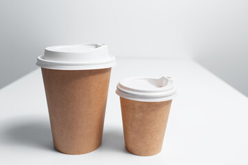 Close-up of two paper cups for coffee takeaway on white table.