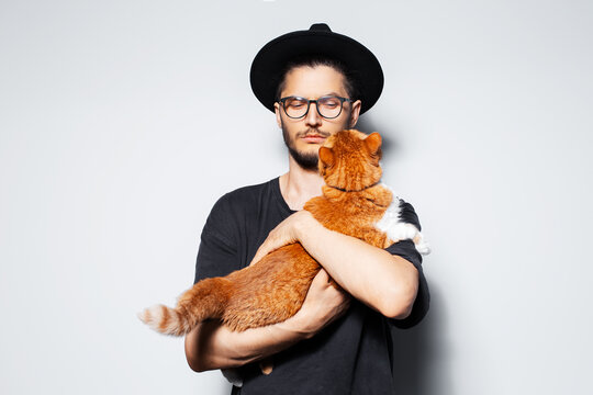 Studio portrait of young handsome man holding a red cat.