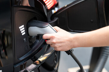 Woman holding plug of electric car charging station 
