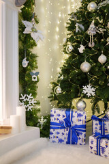 Christmas tree decorated with shiny garland and bulbs in white room. Wrapped present boxes, festive vibes of winter holidays. Close up shot