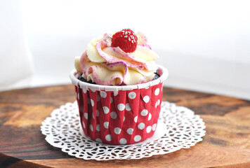 Delicious cupcake with cream and homemade raspberries in paper form