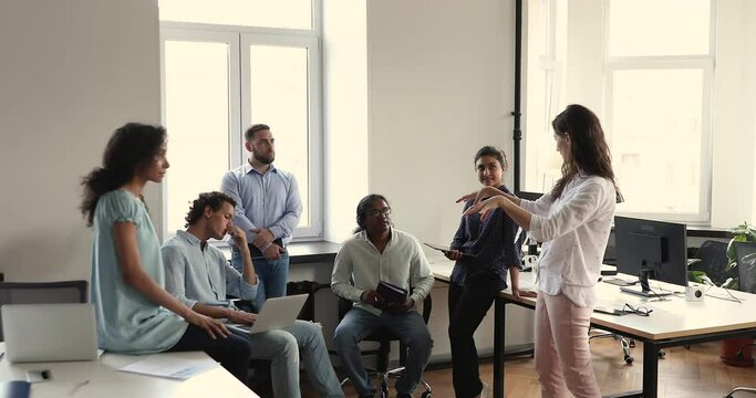 Young female business teacher trainer explain idea propose task to diverse interns trainees on coaching consultation. Multiracial businesspeople group meet on professional workshop at company office