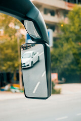 Reflection of a car on the side mirror of intercity coach bus. 