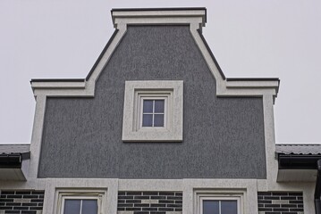 gray attic of a private house with one small white window against a sky