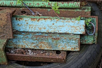 a pile of old rusty blue and brown iron corners and profiles lie on the street