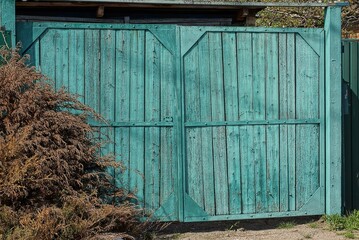 one closed blue green wooden rustic gate outdoors in the street