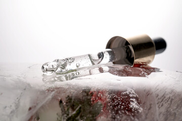 Pipette on a large piece of ice with frozen flowers.