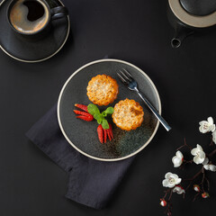 Muffins on a plate are decorated with strawberries and fresh mint. View from above. Dark background.