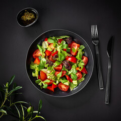 Healthy vegetable salad of fresh tomatoes, cucumbers, onions, spinach, lettuce and sesame on a plate. Diet menu. View from above.