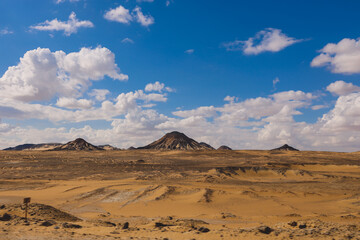 Fototapeta na wymiar Panoramic View to the Sandy Hills in the Black Desert, is National park in the Farafra Oasis, Egypt