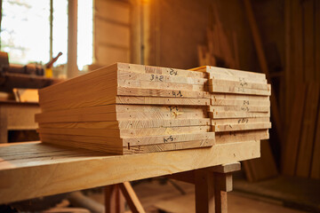 Wooden boards are stacked in a sawmill or carpentry shop. Sawing drying and marketing of wood. Industrial background