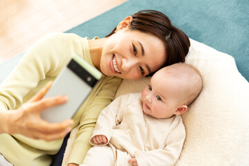 Obraz na płótnie Canvas スマートフォンで写真を撮影する母親と赤ちゃん