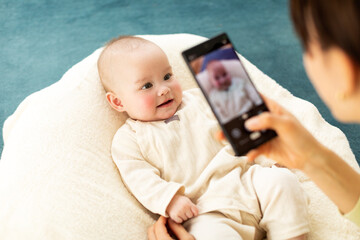 スマートフォンで赤ちゃんの写真を撮る母親