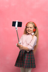 The little girl makes a selfie on the phone. Schoolgirl talks about video communication on a smartphone.