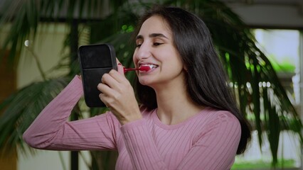 Close-up of a young girl of oriental appearance looking in the mirror and brushing her teeth with a toothbrush. Girl in braces