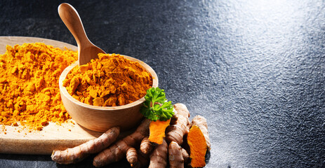 Composition with a bowl of ground turmeric and its fresh rhizome