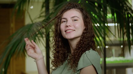 Close-up of a young woman with brown curly hair. The girl is flirting on camera. Portrait of a girl