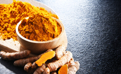 Composition with a bowl of ground turmeric and its fresh rhizome