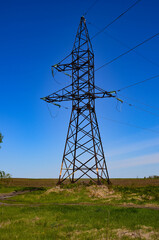 High-voltage power lines in the field against the blue sky