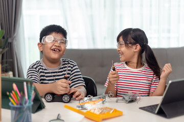 two Asian children having fun learning coding together, learning remotely at home, STEM science,...
