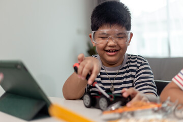 Young asia student remotely learn online at home in coding robot car and electronic board cable in STEM, STEAM, mathematics engineer science technology computer code in robotics for kids.