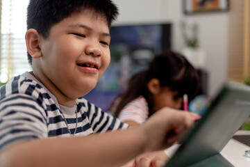 Asian boys and girls enjoy online learning by taking notes and using tablets at home.