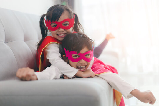  happy and confident young kids playing and dressing up as superhero together in bedroom