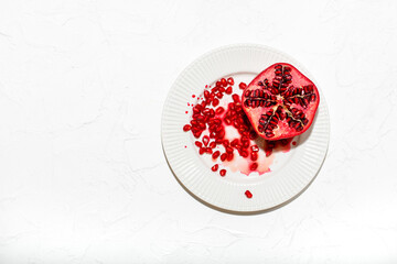 A pomegranate cut in half lies on a table covered with a white tablecloth. 