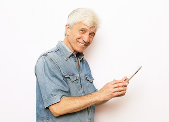 Mature gray-haired male wearing jeans shirt using portable computer over white background.