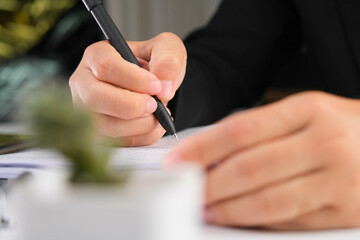 Close up of businesswoman hands writing at business document at workplace.
