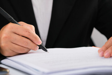 Close up of businesswoman hands writing at business document at workplace.