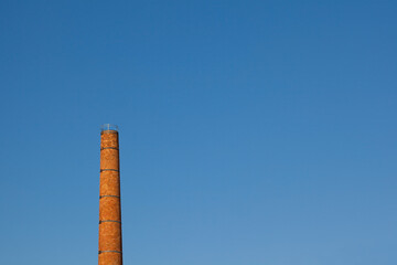 Brick chimney against blue sky, sunset.