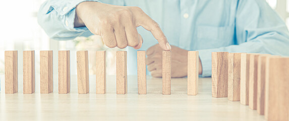 Close-up hand prevent wooden block not falling domino concepts of financial risk management and...