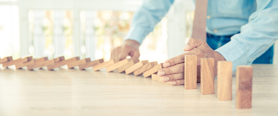 Close-up hand prevent wooden block not falling domino concepts of financial risk management and...