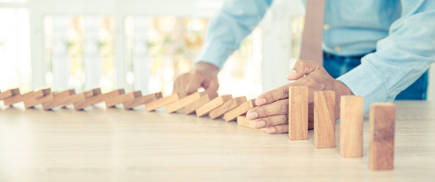 Close-up Hand Prevent Wooden Block Not Falling Domino Concepts Of Financial Risk Management And Strategic Planning And Business Challenge Plan.