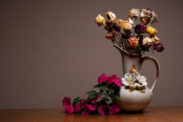A beautiful bouquet of wilted dried out roses on an isolated plain background in a vintage vase flower pot with top lighting
