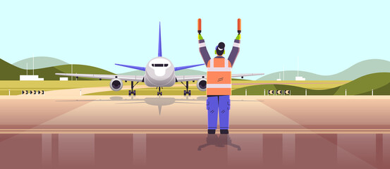 Obraz na płótnie Canvas aviation marshaller supervisor in uniform navigate with light sticks air traffic controller airline worker in signal vest