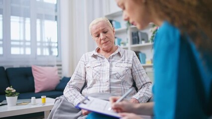 Female doctor listening to senior woman's complaints, filling out medical form