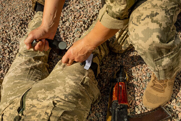 Army medics practice applying a tourniquet to the leg of a wounded soldier. Combat tactical...